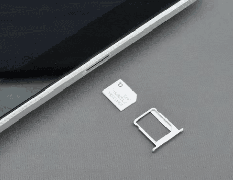 sim card tray and micro sim card on a table next to a smartphone 